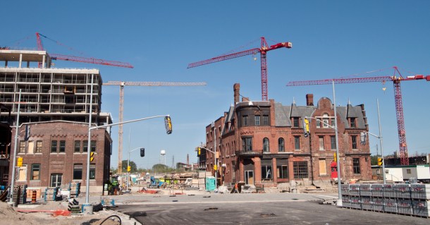 Cranes surrounding old brick building.