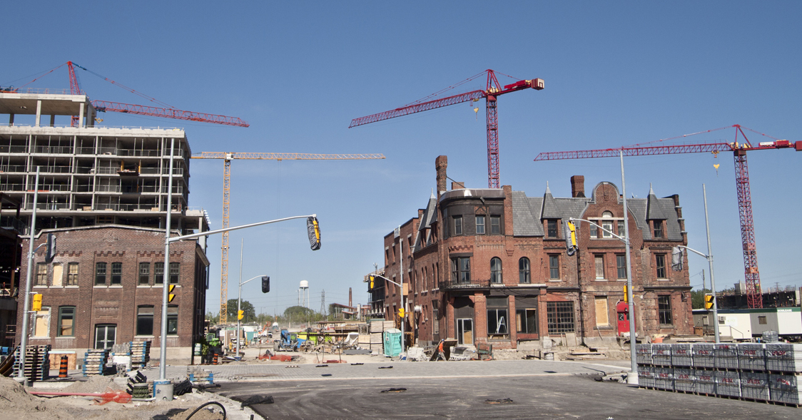 Cranes surrounding old brick building.