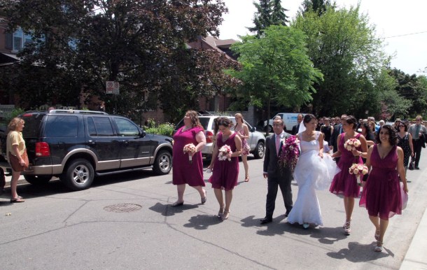 Bystander watching wedding pass by in the street.