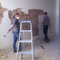 Workers removing plaster from brick walls at Boxcar Social.