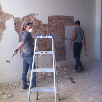Workers removing plaster from brick walls at Boxcar Social.