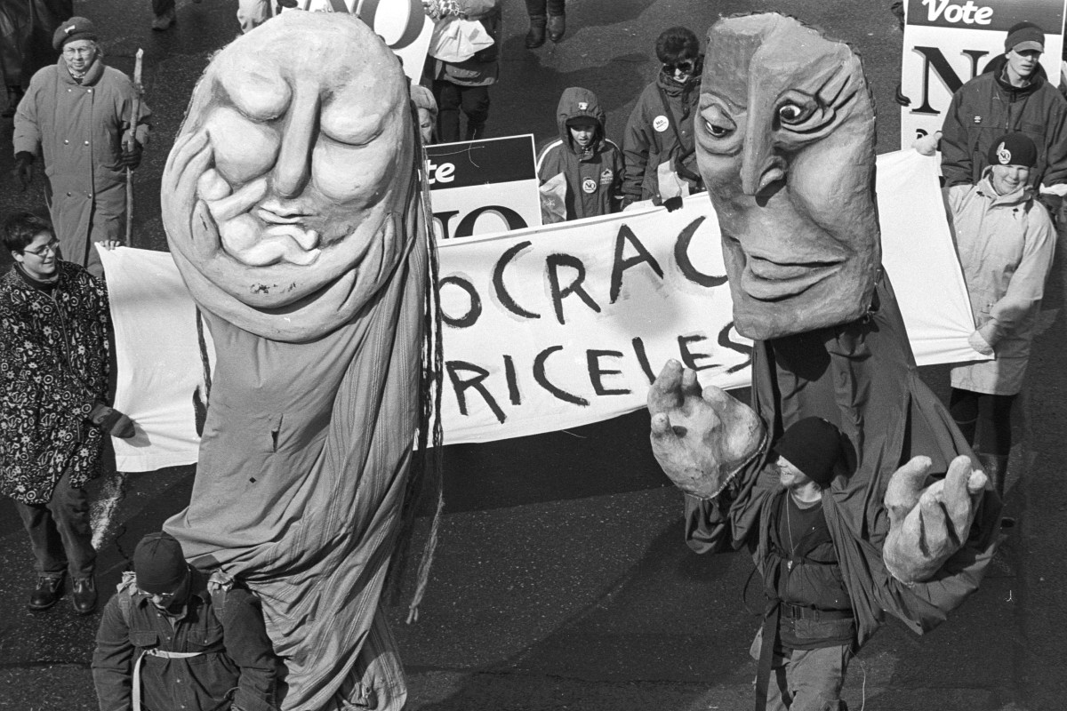 Giant puppets march against the megacity.